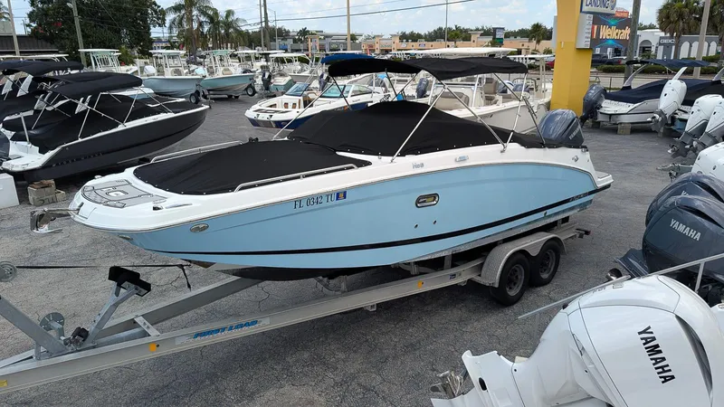 Slide: The Image of 2024 Four Winns HD8 OB boat on trailer, blue hull, covered, in dealership lot. - 2