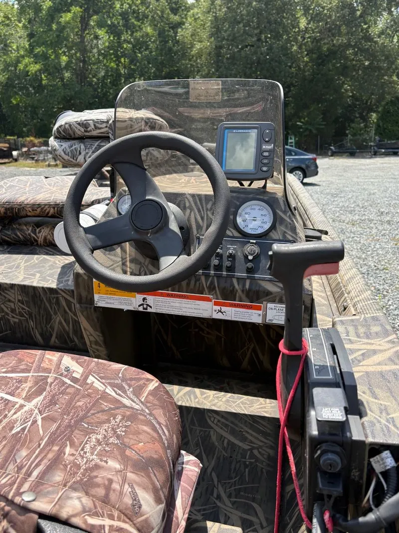 Slide: The Image of 2012 Crestliner 16 Ambush boat interior with steering wheel, gauges, and camouflage seating. - 11