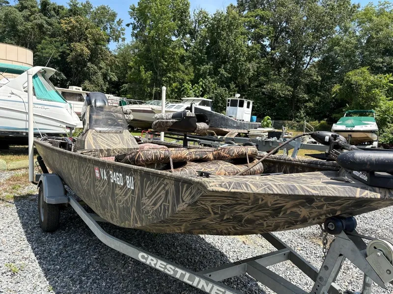 Slide: The Image of 2012 Crestliner 16 Ambush boat with camouflage design on a trailer, surrounded by other boats. - 2