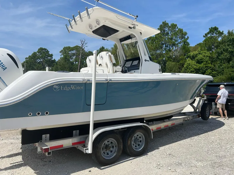Slide: The Image of 2019 Edgewater 262CC boat on trailer, parked outdoors under clear sky. - 1