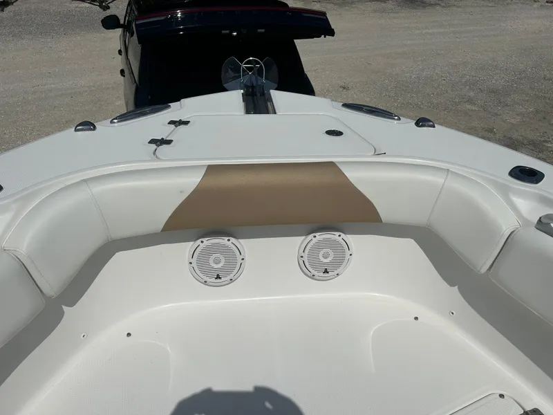 Slide: The Image of 2019 Edgewater 262CC boat interior with seating and speakers, parked on a trailer. - 14