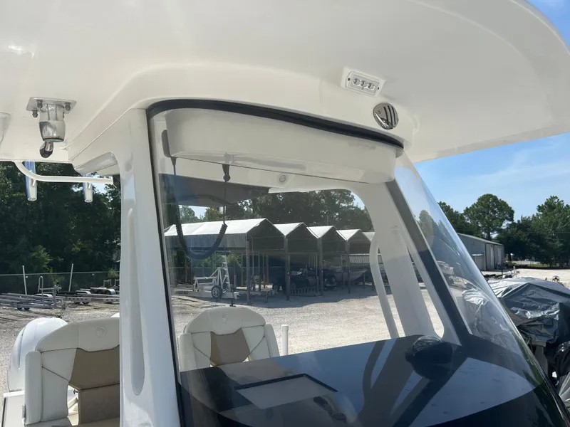Slide: The Image of 2019 Edgewater 262CC boat interior with seating and dashboard, parked outdoors. - 15