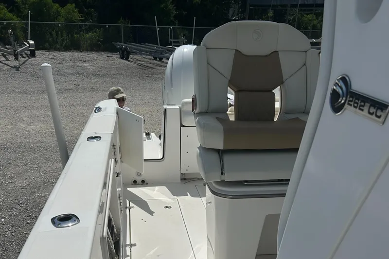 Slide: The Image of 2019 Edgewater 262CC boat interior with seating and storage, parked on gravel. - 18