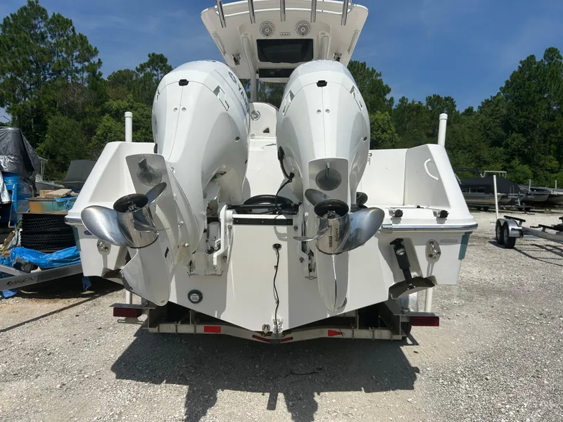 Slide: The Image of 2019 Edgewater 262CC boat with dual outboard motors, parked on a gravel lot. - 2