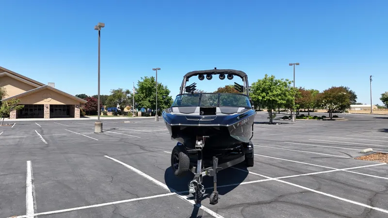 Slide: The Image of 2025 MasterCraft NXT22 boat on trailer in empty parking lot. - 14