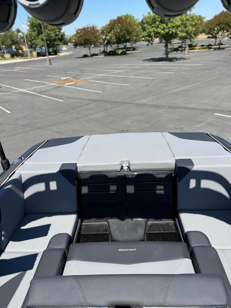 Slide: The Image of 2025 MasterCraft NXT22 boat interior with gray seating in a parking lot. - 23