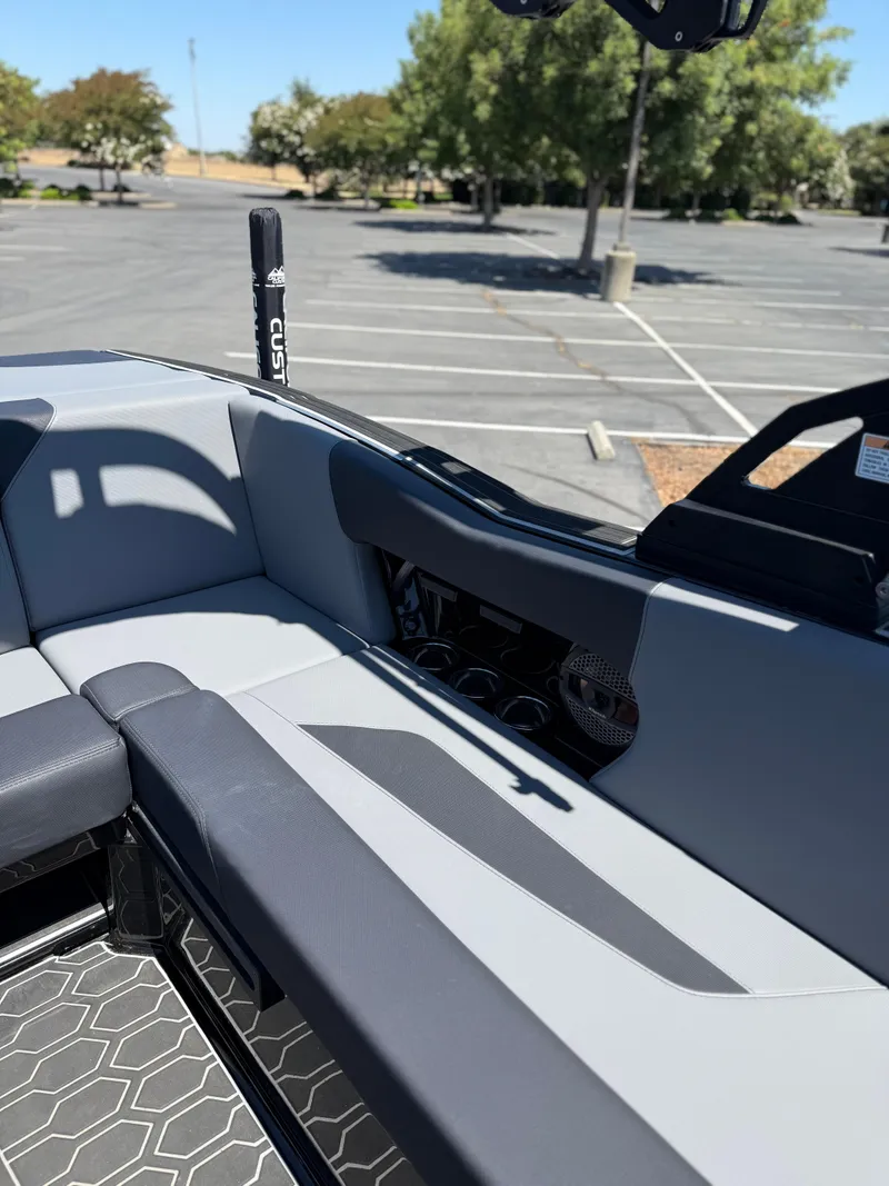 Slide: The Image of 2025 MasterCraft NXT22 boat interior with gray seating and hexagonal flooring in a parking lot. - 24