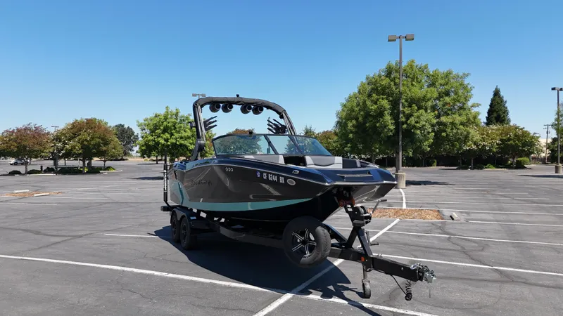 Slide: The Image of 2025 MasterCraft NXT22 boat on trailer in empty parking lot, clear blue sky. - 9