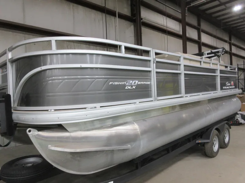 Slide: The Image of 2024 Sun Tracker Fishin' Barge 20 DLX pontoon boat in a warehouse setting. - 2