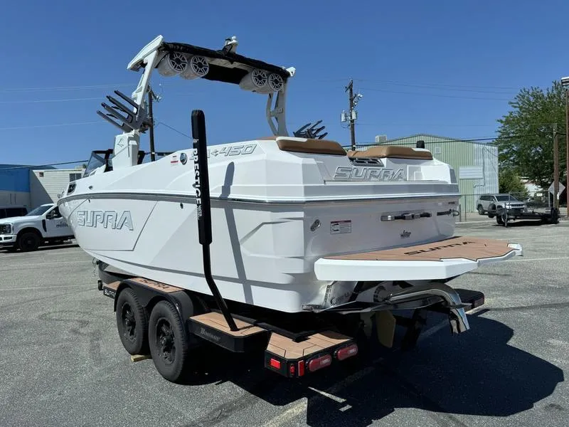 Slide: The Image of 2023 Supra SA boat on trailer, white exterior, parked outdoors under clear sky. - 7