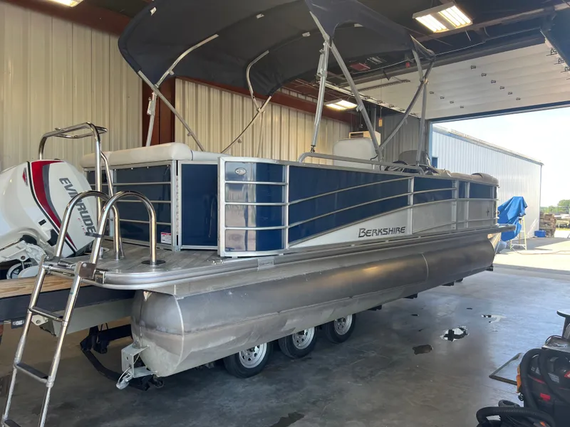Slide: The Image of 2018 Berkshire 23 CLSTS2.75 pontoon boat in a garage, featuring an Evinrude outboard motor. - 3