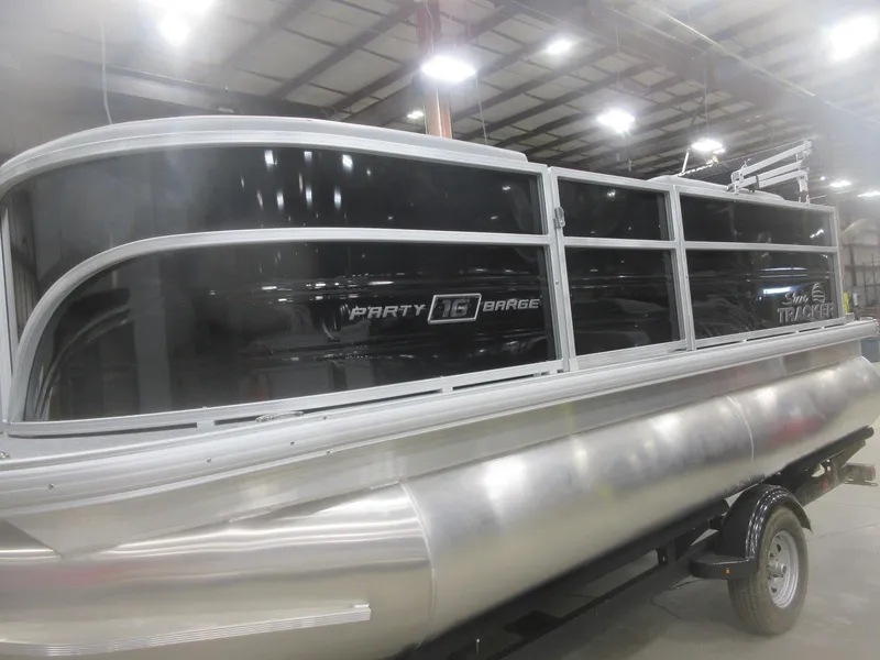 Slide: The Image of 2026 Sun Tracker Party Barge 16 DLX pontoon boat in a showroom. - 2