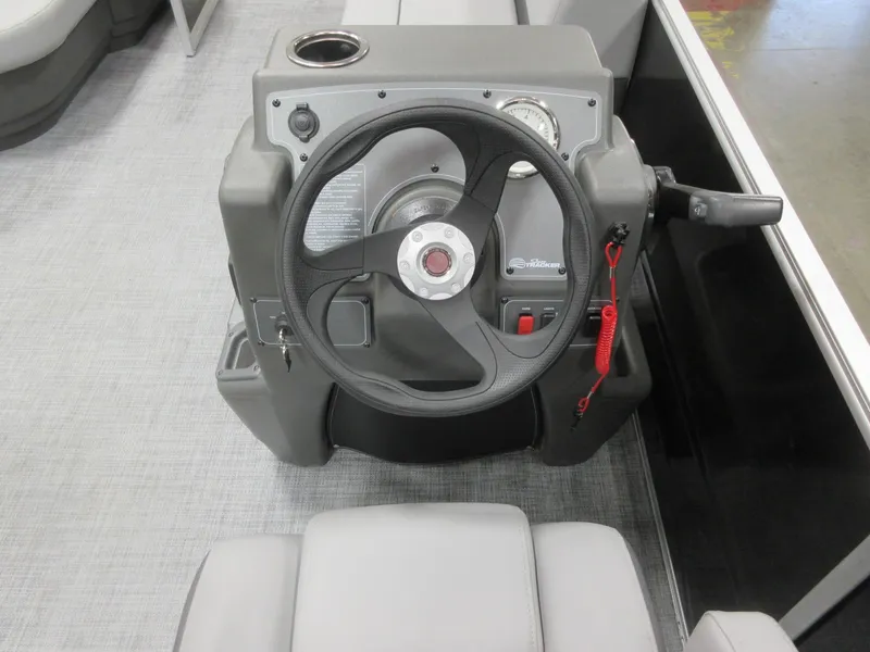 Slide: The Image of Steering console of 2026 Sun Tracker Party Barge 16 DLX with modern controls and cup holder. - 8