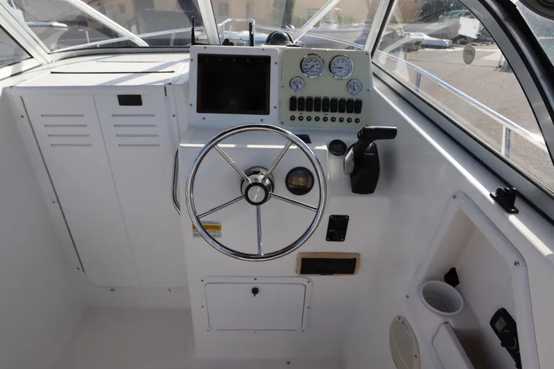 Slide: The Image of 2004 Sea Pro 220 Walk Around boat cockpit with steering wheel and control panel. - 20