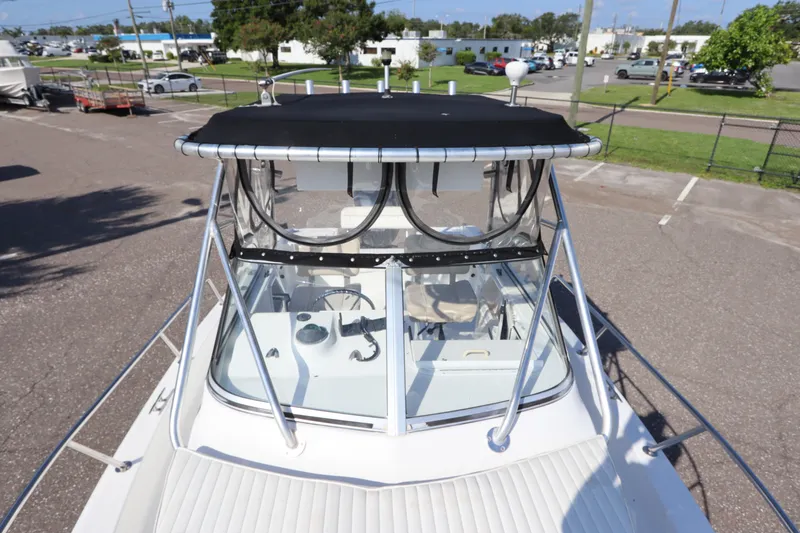 Slide: The Image of 2004 Sea Pro 220 Walk Around boat with black canopy, docked in a parking area. - 26