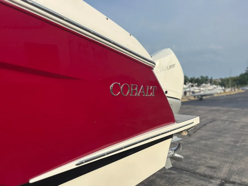 Slide: The Image of 2024 Cobalt R8 Outboard boat with red and white exterior, docked outdoors. - 3