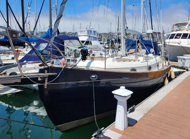 Slide: The Image of 1983 Hans Christian HC33 sailboat docked at a marina under clear blue skies. - 0