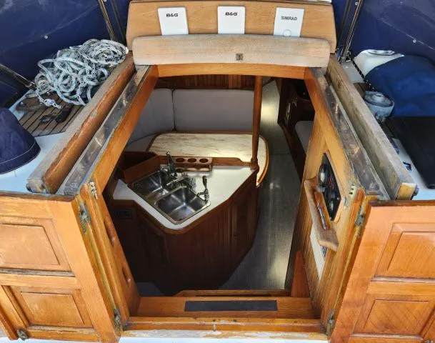 Slide: The Image of 1983 Hans Christian HC33 yacht interior with wooden cabinetry and compact kitchen area. - 2