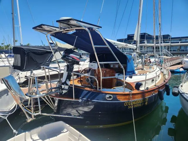 Slide: The Image of 1983 Hans Christian HC33 sailboat docked in marina, featuring blue hull and Mercury outboard motor. - 46