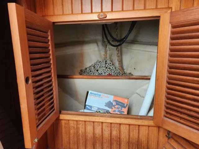 Slide: The Image of Wooden cabinet with open doors, revealing anchor chain and Amarine-made product box inside. Hans Christian HC33, 1983. - 49