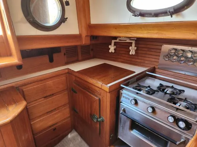 Slide: The Image of 1983 Hans Christian HC33 yacht kitchen with wooden cabinetry and stainless steel stove. - 9