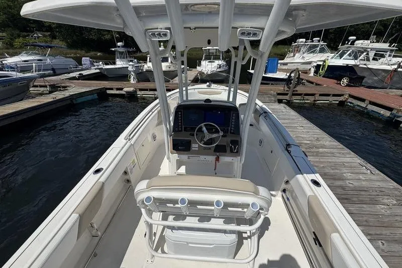 Slide: The Image of 2021 Robalo R242 Center Console boat docked at marina, featuring helm and seating area. - 8