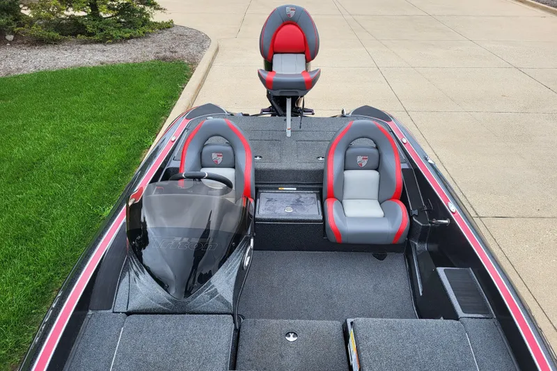 Slide: The Image of 2023 Triton 179 TrX boat interior with gray and red seating, parked on concrete. - 3