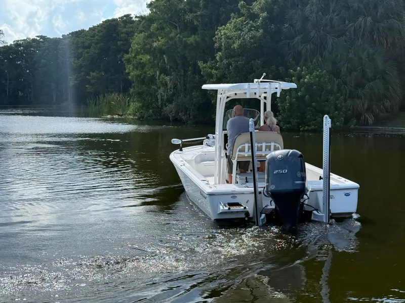 Slide: The Image of 2021 Tidewater 2410 Bay Max boat cruising on a serene lake with lush greenery. - 10