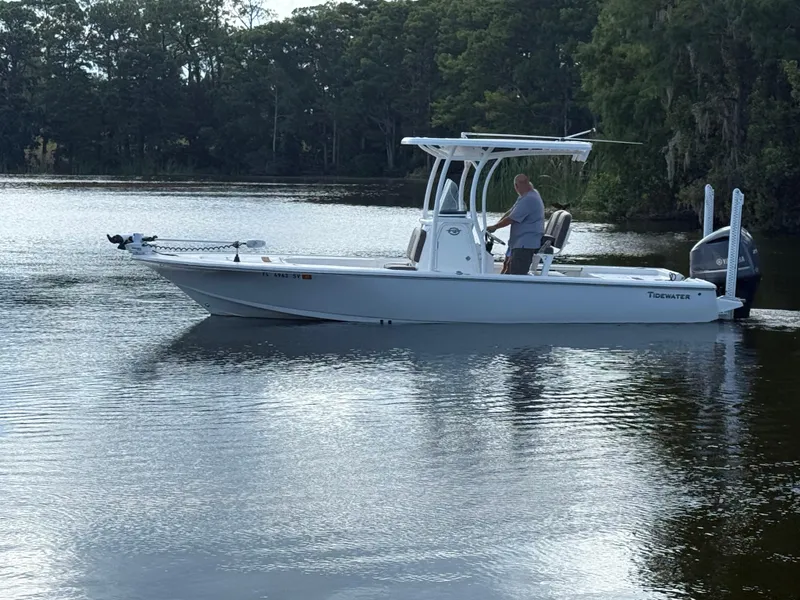 Slide: The Image of 2021 Tidewater 2410 Bay Max boat on calm water with trees in the background. - 2