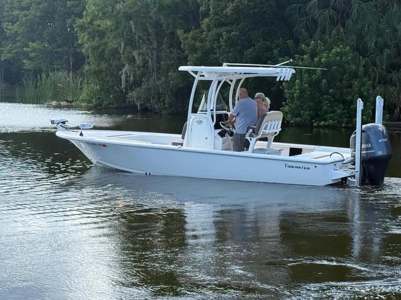 Slide: The Image of 2021 Tidewater 2410 Bay Max boat on calm water with lush greenery background. - 4
