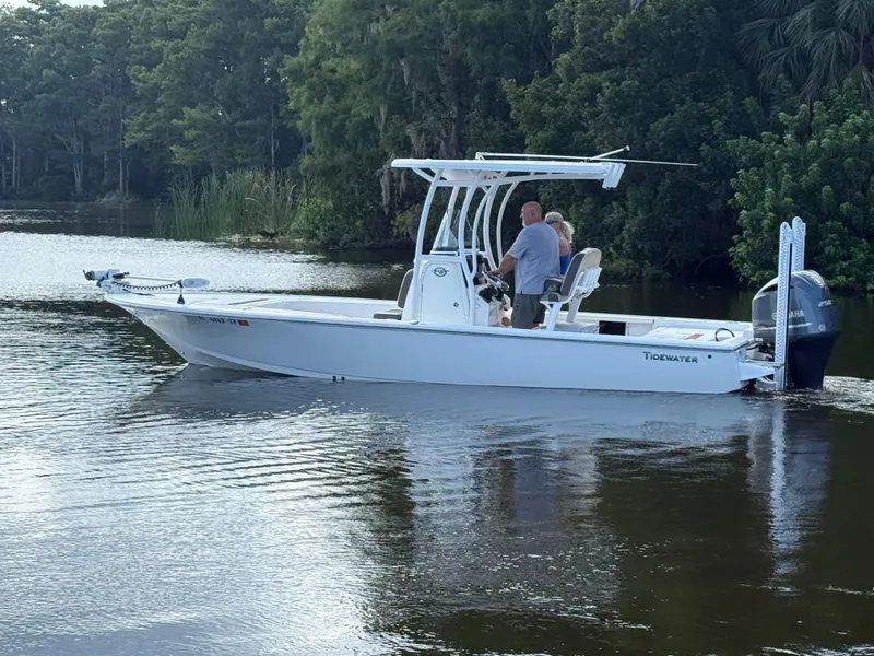 Slide: The Image of 2021 Tidewater 2410 Bay Max boat cruising on a calm river with lush greenery. - 5