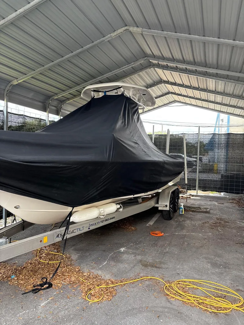 Slide: The Image of 2021 Tidewater 2410 Bay Max boat covered in black tarp under a metal shelter. - 66