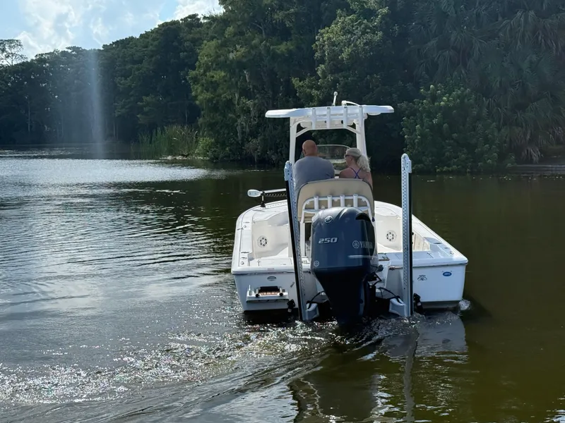 Slide: The Image of 2021 Tidewater 2410 Bay Max boat cruising on a serene lake with lush greenery. - 7