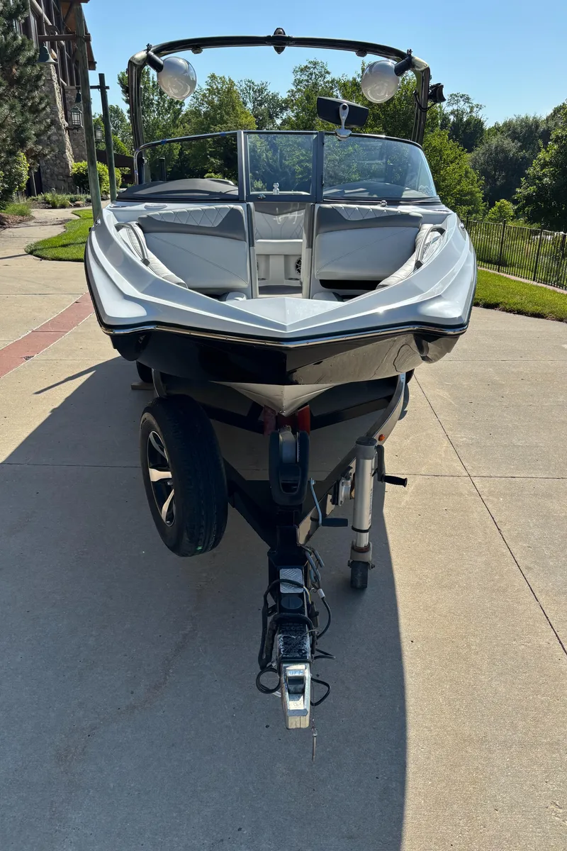 Slide: The Image of 2014 Tigé RZR boat on trailer, parked on driveway, surrounded by greenery. - 3