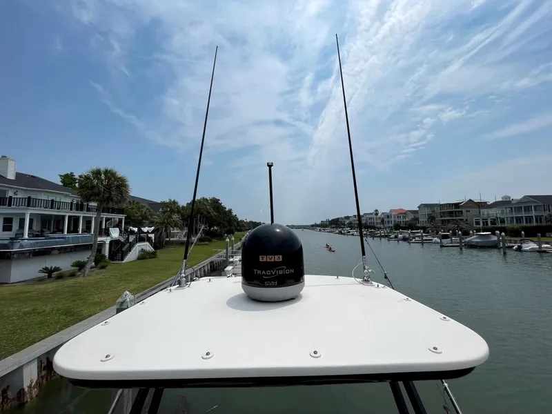 Slide: The Image of 2020 Scout 420 LXF boat on a canal, surrounded by waterfront homes under a partly cloudy sky. - 20