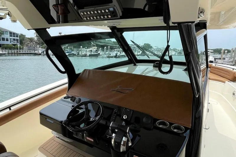 Slide: The Image of 2020 Scout 420 LXF boat helm with modern controls, docked in a marina. - 25