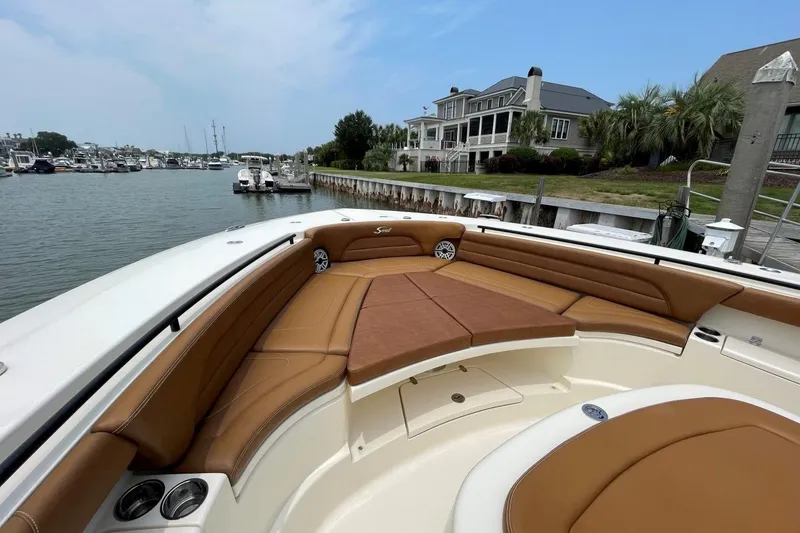 Slide: The Image of 2020 Scout 420 LXF boat with luxurious seating, docked near waterfront homes. - 4