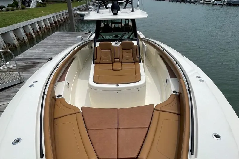 Slide: The Image of 2020 Scout 420 LXF boat with tan seating, docked by the water. - 8
