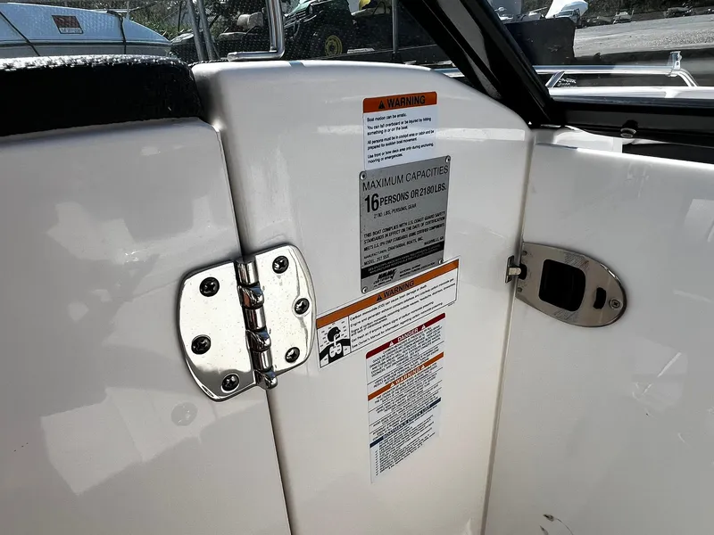 Slide: The Image of 2018 Chaparral 257 SSX boat interior with capacity warning label and metal hinge. - 24