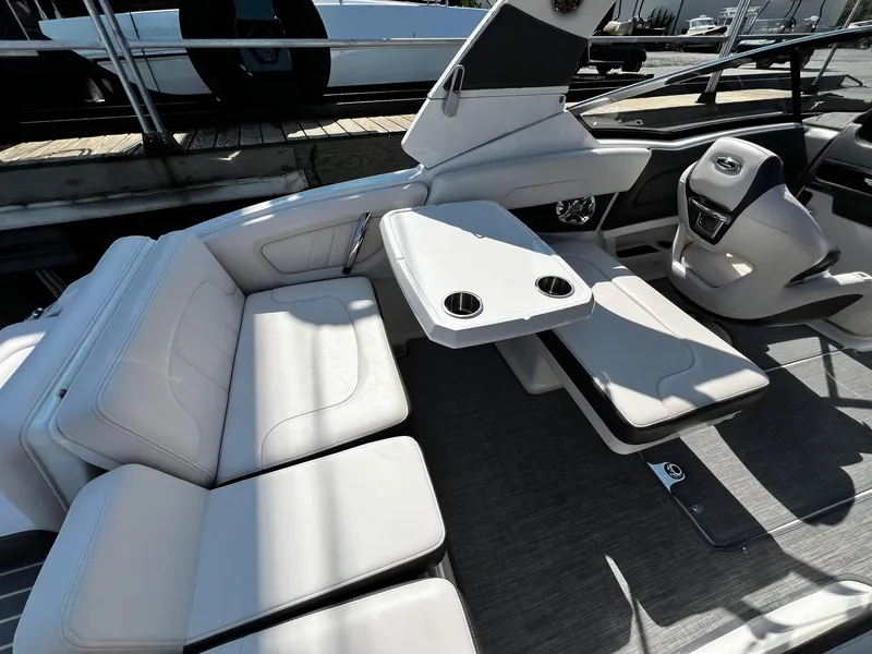 Slide: The Image of 2018 Chaparral 257 SSX boat interior with white seating and table, docked at marina. - 9