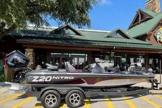 Slide: The Image of 2023 Nitro Z20 boat on trailer outside a rustic building under a clear blue sky. - 16