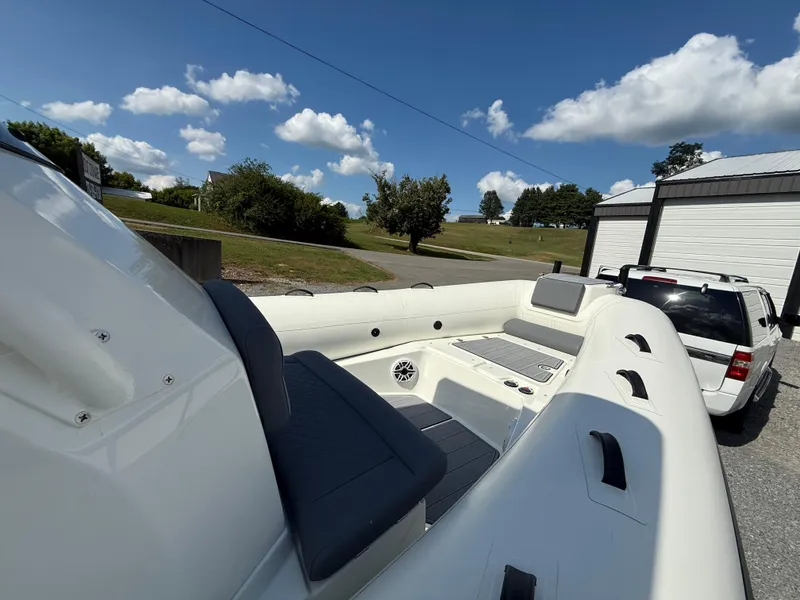 Slide: The Image of 2026 Brig Eagle 8 boat interior with seating, parked near a white SUV under a blue sky. - 15