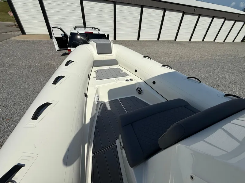 Slide: The Image of 2026 Brig Eagle 8 boat interior with seating, parked near a storage facility. - 23
