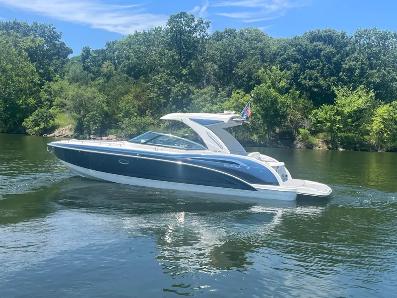 Slide: The Image of 2023 Formula 350 Crossover Bowrider I/O cruising on a serene lake with lush greenery. - 28