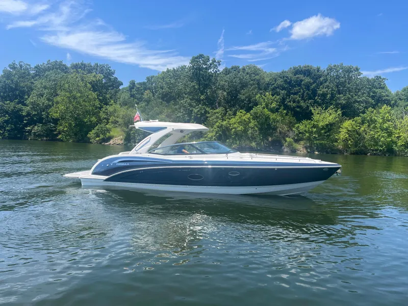 Slide: The Image of 2023 Formula 350 Crossover Bowrider I/O on a scenic lake under a clear blue sky. - 36