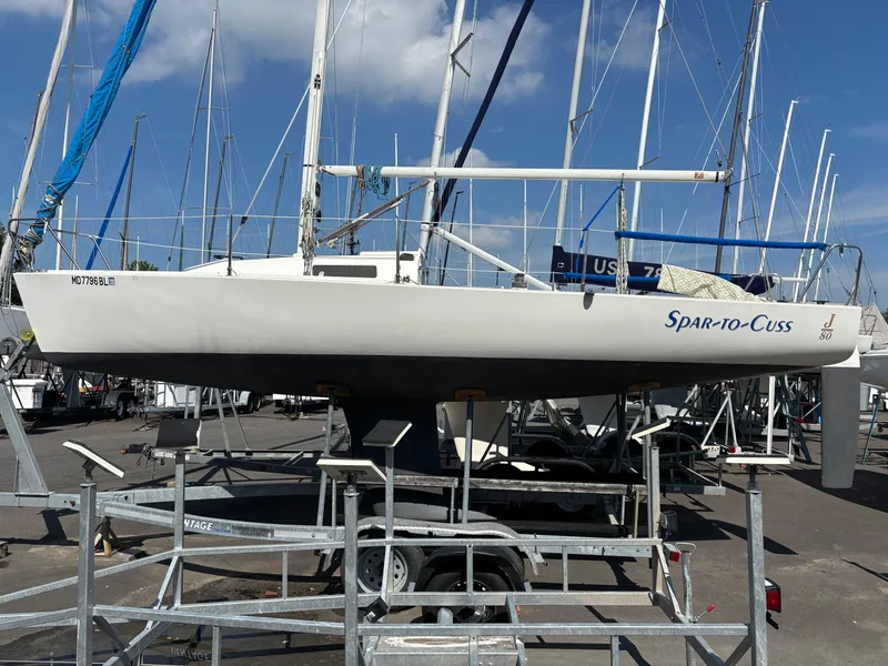 Slide: The Image of 1997 J Boats J/80 sailboat on trailer, named "Spar-to-Cuss," in a marina setting. - 0