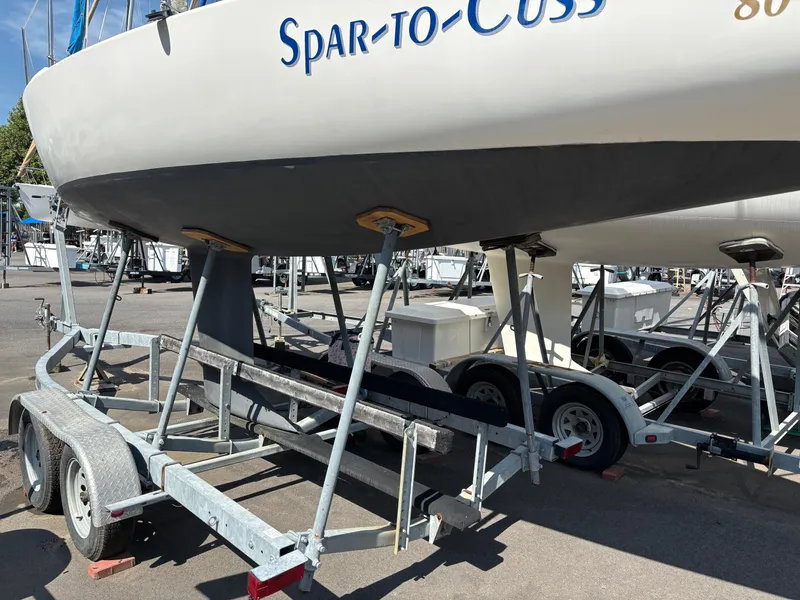 Slide: The Image of 1997 J Boats J/80 sailboat on trailer, named "Spar-To-Cuss," in a marina setting. - 1