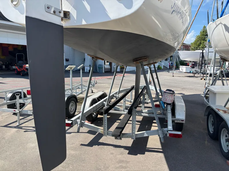 Slide: The Image of 1997 J Boats J/80 sailboat on trailer, showing rudder and hull in a marina setting. - 2