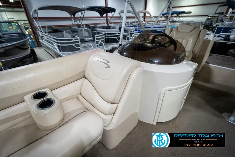 Slide: The Image of 2014 Bennington 2275GCW pontoon boat interior in showroom, featuring beige seating and helm. - 30