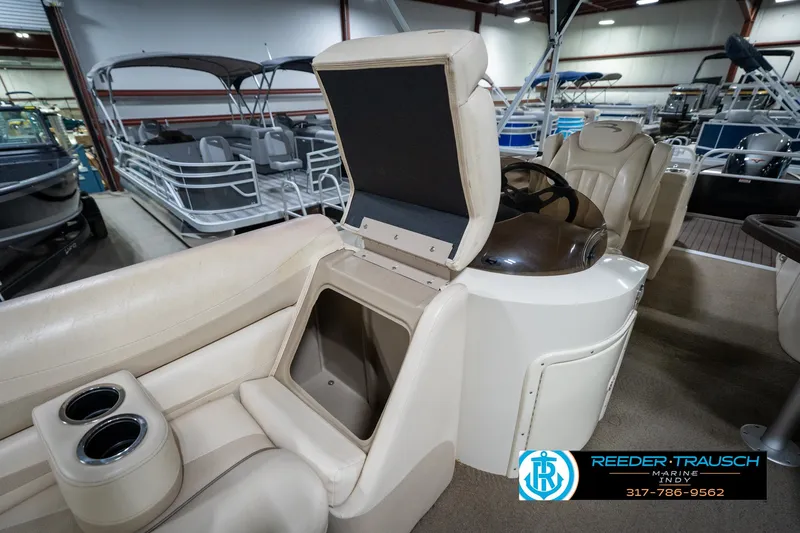 Slide: The Image of 2014 Bennington 2275GCW pontoon boat interior in a showroom, featuring beige seating and helm. - 31